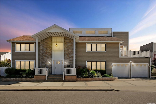 view of front of house featuring driveway, a balcony, a garage, and stone siding