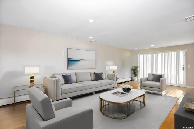 living area with a baseboard heating unit, light wood-style floors, recessed lighting, and baseboards