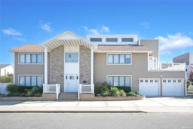 view of front of property featuring driveway, a balcony, and stone siding