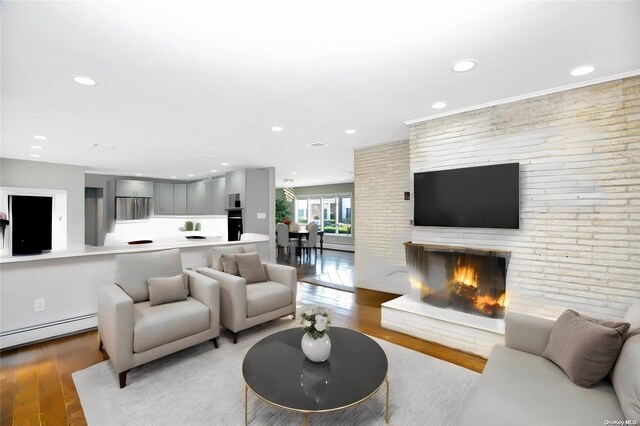 living room featuring light wood-type flooring, recessed lighting, a fireplace, and baseboard heating