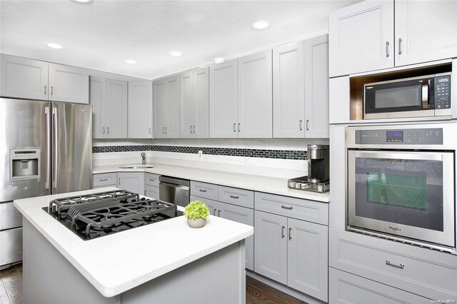 kitchen with appliances with stainless steel finishes, light countertops, a kitchen island, dark wood finished floors, and recessed lighting