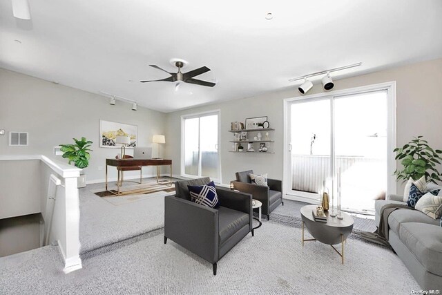 carpeted living room featuring track lighting, a ceiling fan, and baseboards