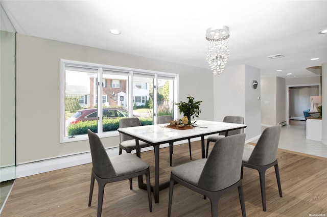 dining area featuring light hardwood / wood-style flooring, a baseboard heating unit, and an inviting chandelier