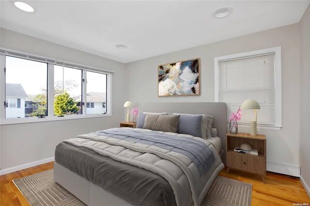 bedroom featuring a baseboard radiator, baseboards, light wood-style floors, and recessed lighting