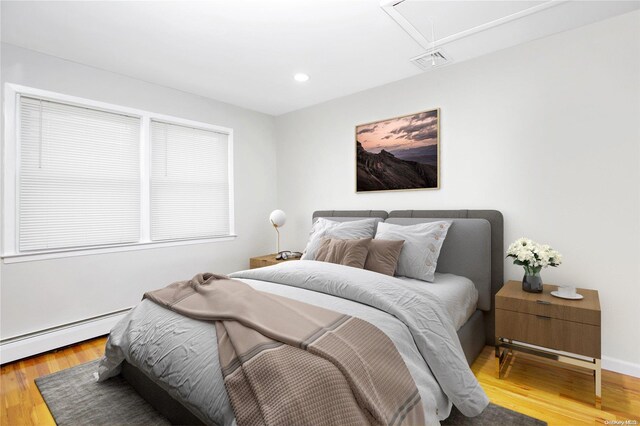 bedroom with attic access, light wood-style flooring, baseboard heating, and recessed lighting