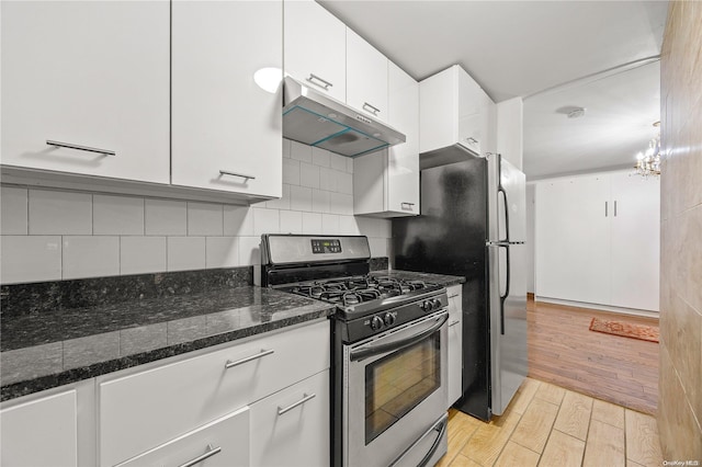 kitchen with white cabinets, light hardwood / wood-style flooring, gas range, decorative backsplash, and dark stone countertops