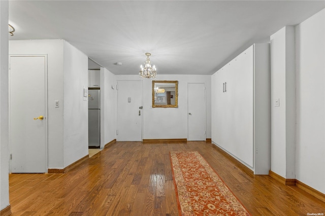 corridor with an inviting chandelier and hardwood / wood-style flooring