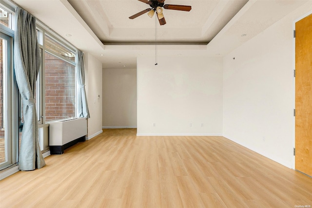 spare room featuring light hardwood / wood-style flooring, a raised ceiling, and ceiling fan