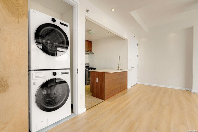 washroom featuring light hardwood / wood-style flooring and stacked washer / drying machine