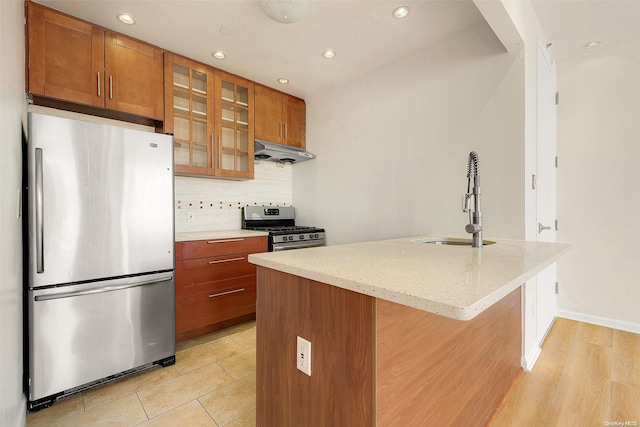 kitchen featuring backsplash, a kitchen island with sink, ventilation hood, sink, and stainless steel appliances