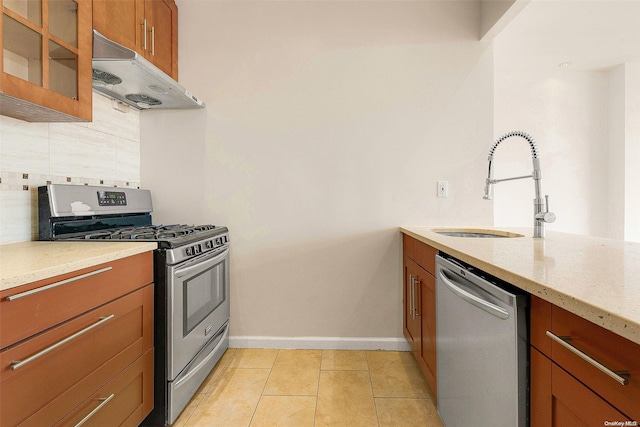 kitchen featuring light stone countertops, appliances with stainless steel finishes, backsplash, sink, and light tile patterned floors