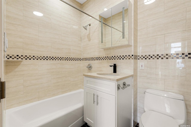 full bathroom featuring vanity, toilet, tile walls, and tiled shower / bath