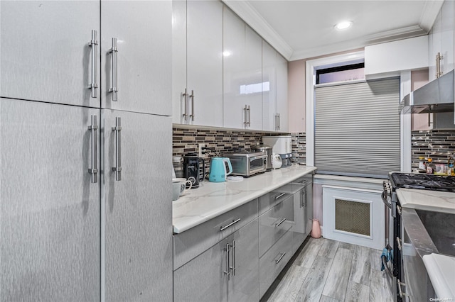 kitchen with light hardwood / wood-style flooring, crown molding, refrigerator, exhaust hood, and stainless steel range with gas stovetop