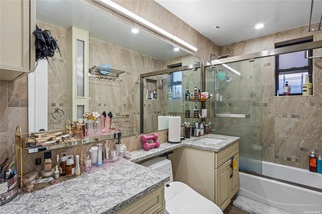 full bathroom featuring vanity, enclosed tub / shower combo, tile walls, and toilet