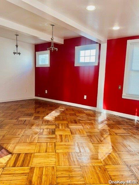 spare room featuring parquet floors and beamed ceiling