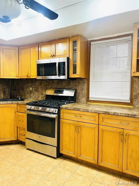 kitchen with backsplash, sink, ceiling fan, appliances with stainless steel finishes, and light tile patterned flooring