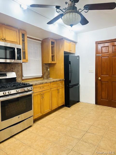 kitchen with light stone countertops, decorative backsplash, ceiling fan, and stainless steel appliances