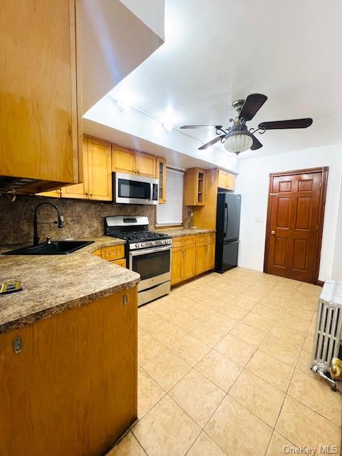 kitchen featuring ceiling fan, sink, tasteful backsplash, light tile patterned floors, and appliances with stainless steel finishes