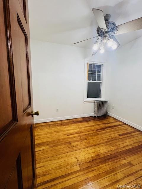 unfurnished room with ceiling fan, wood-type flooring, and radiator heating unit