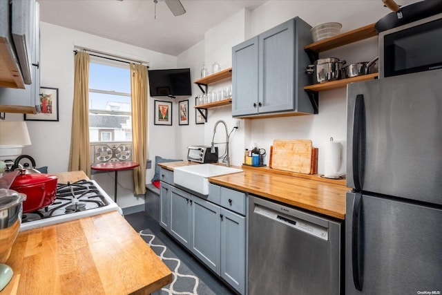 kitchen with appliances with stainless steel finishes, ceiling fan, butcher block counters, and gray cabinetry