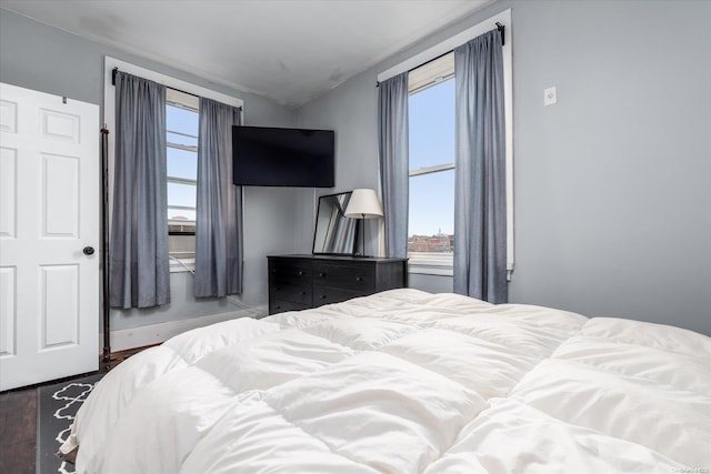 bedroom with dark hardwood / wood-style floors, vaulted ceiling, and multiple windows