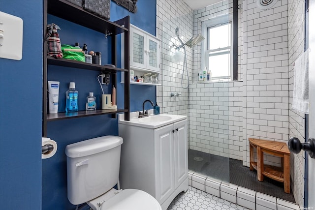 bathroom with a tile shower, tile patterned floors, vanity, and toilet