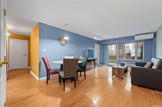 dining room with light hardwood / wood-style flooring and an AC wall unit