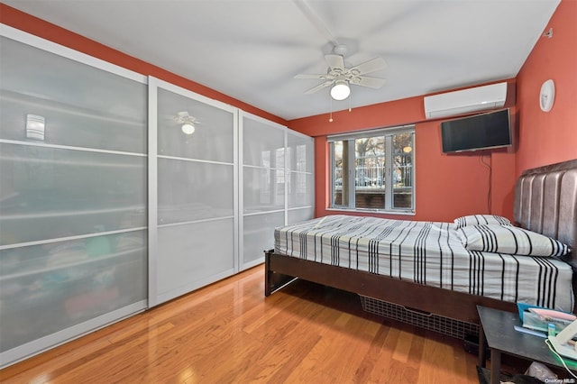 bedroom featuring a wall mounted air conditioner, ceiling fan, and light wood-type flooring