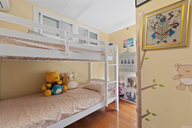 bedroom featuring hardwood / wood-style flooring and a wall unit AC