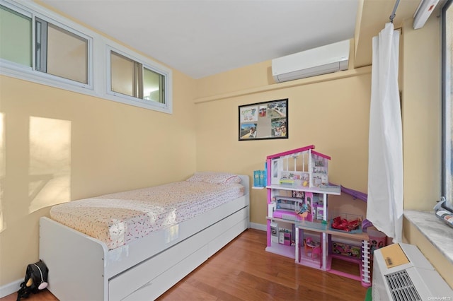 bedroom with a wall mounted AC and hardwood / wood-style floors