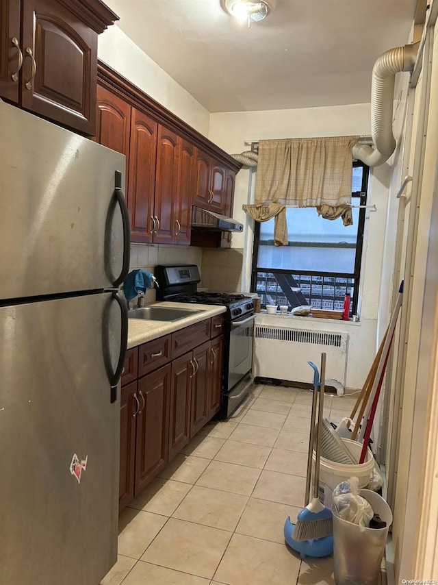 kitchen featuring stainless steel refrigerator, radiator, sink, black gas stove, and light tile patterned flooring