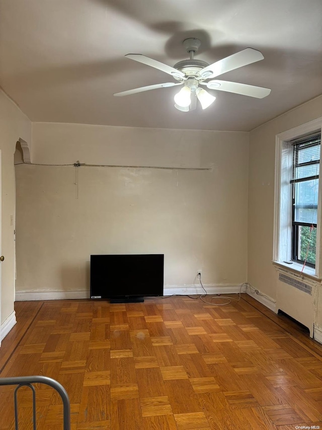 empty room with light parquet flooring, radiator, and ceiling fan