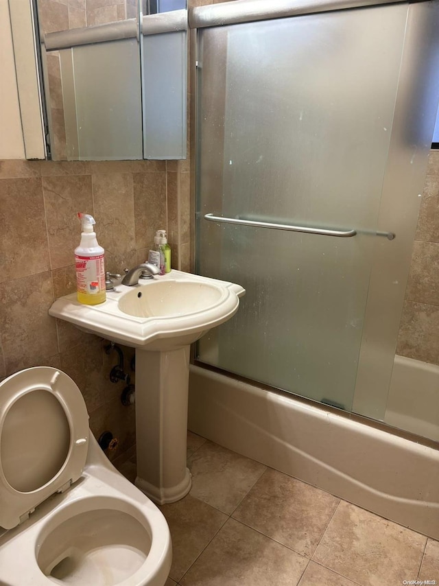 bathroom featuring decorative backsplash, tile patterned floors, tile walls, and bath / shower combo with glass door