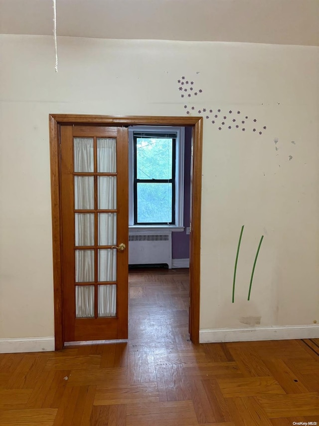 spare room featuring parquet floors, radiator, and french doors