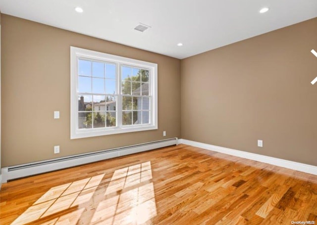 spare room featuring a baseboard radiator and light hardwood / wood-style floors