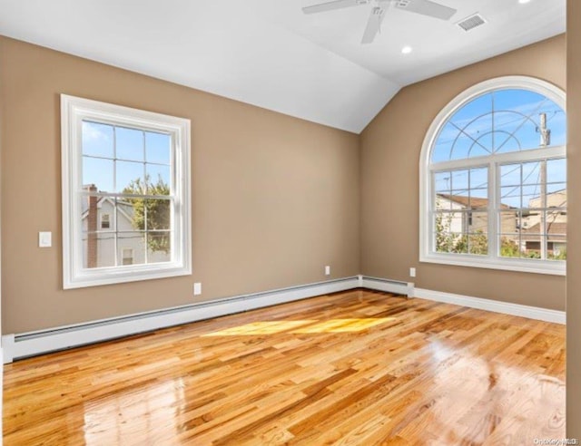 unfurnished room featuring light hardwood / wood-style floors, baseboard heating, a wealth of natural light, and lofted ceiling