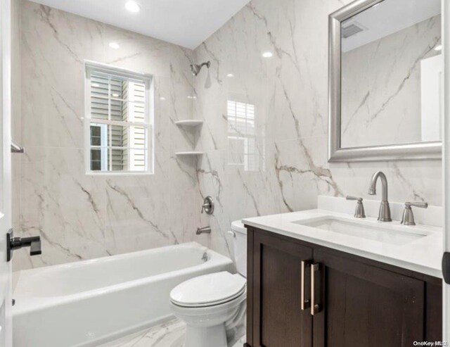 full bathroom with toilet, vanity, tile walls, and tiled shower / bath