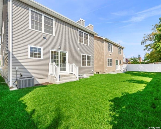 back of property with central air condition unit and a yard