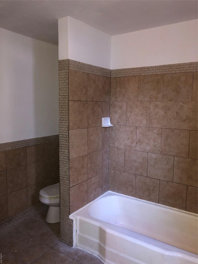 bathroom with toilet, tile patterned floors, and tile walls