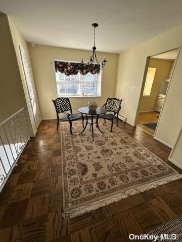 dining space with dark parquet floors and an inviting chandelier