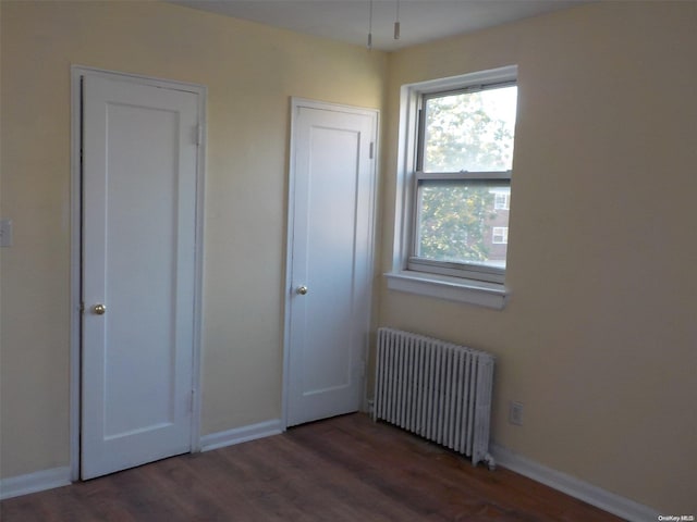 unfurnished bedroom with dark hardwood / wood-style floors and radiator