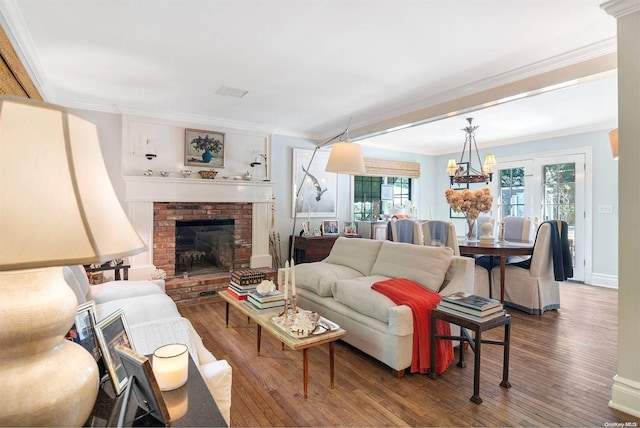 living room with a fireplace, hardwood / wood-style flooring, crown molding, and a notable chandelier