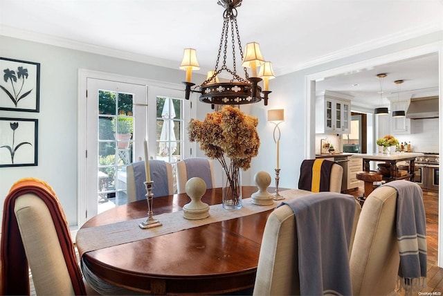 dining room with hardwood / wood-style floors, ornamental molding, and an inviting chandelier