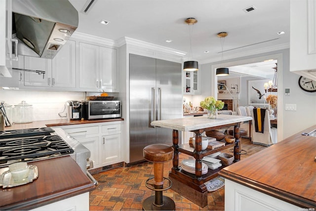 kitchen with stainless steel appliances, ventilation hood, backsplash, decorative light fixtures, and white cabinets