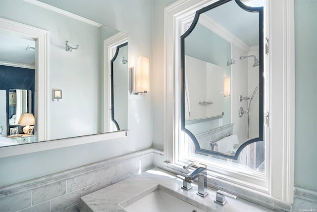 bathroom featuring a tile shower, vanity, and ornamental molding