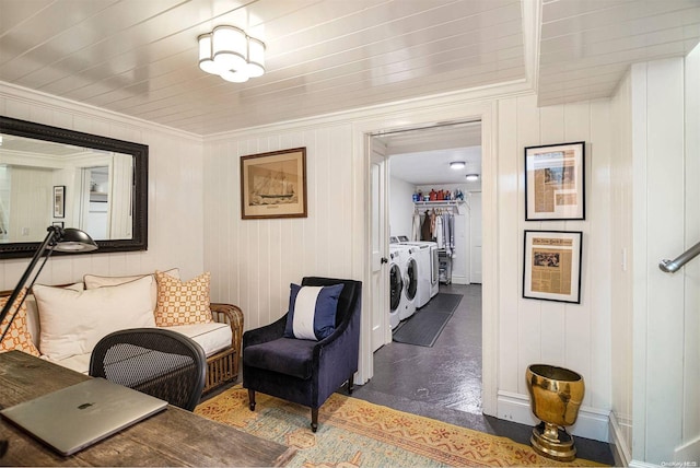 sitting room with crown molding, washer and dryer, and wood walls