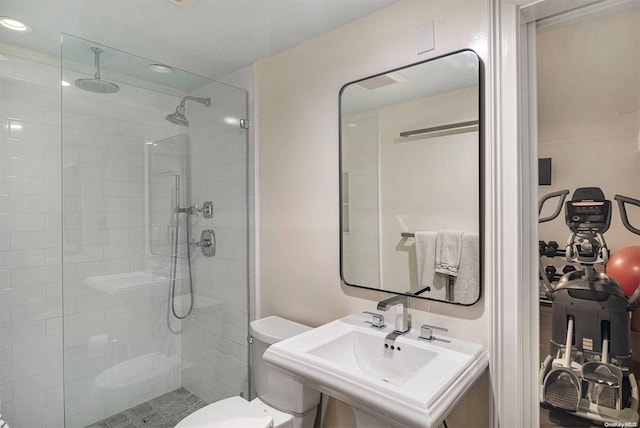 bathroom featuring tiled shower, toilet, and sink