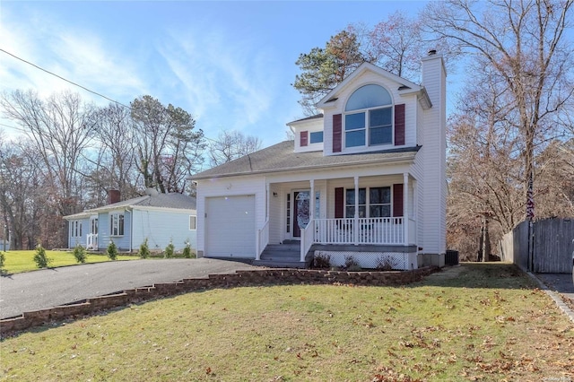 view of front of house featuring covered porch, a garage, and a front lawn