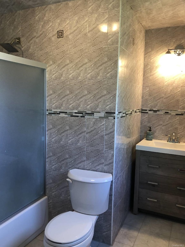 full bathroom with tile patterned floors, toilet, tile walls, vanity, and enclosed tub / shower combo