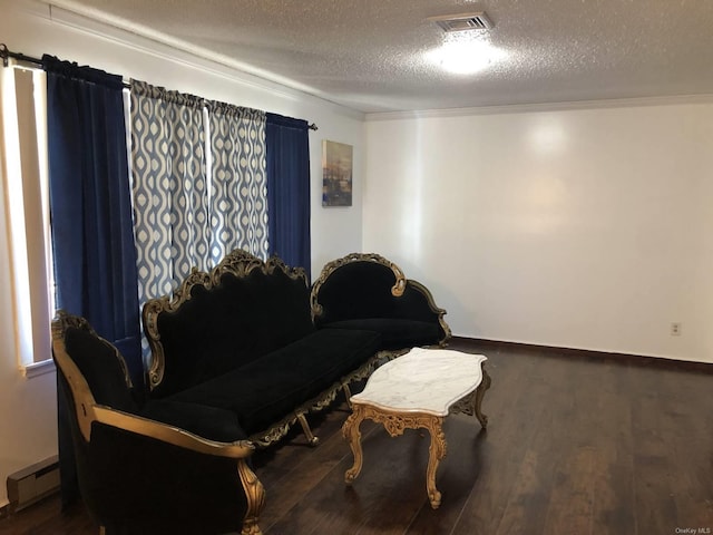 living area with visible vents, a textured ceiling, wood finished floors, and baseboard heating